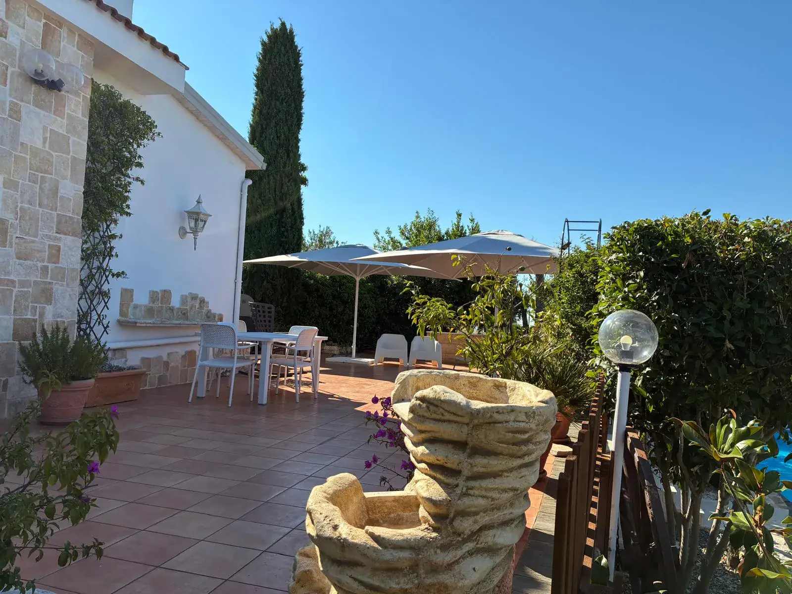 Terrazza con cipresso, vasi in pietra e muro in pietra della villa