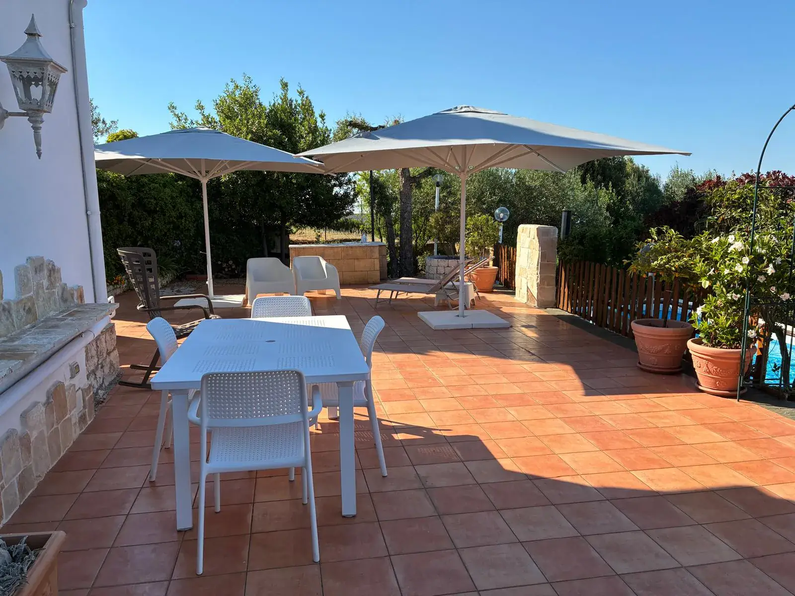 Terrazza in cotto con tavolo da pranzo, ombrelloni e piscina